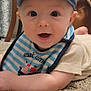 baby, bib, blue_cap, cap, carpet, casual_clothing, child, cute, drool, floor, happy, home, indoor, infant, person, pirate_ship, portrait, smiling, striped_bib, young