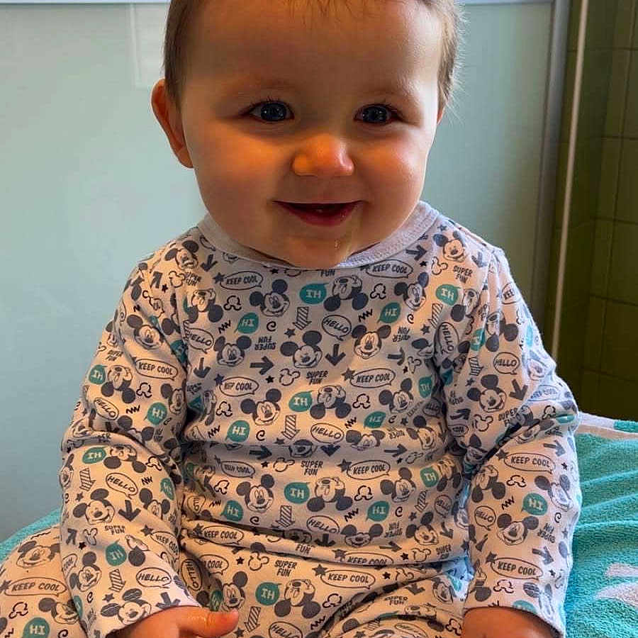 Liam a rejoint le concours — aidez-le/la à gagner de superbes lots ! baby, blanket, bodypart, clothing, door, dress, face, happy, head, mouth, pajamas, pants, person, photography, portrait, quilt, sitting, sleeve, smile, teeth