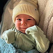 Elijah is registered to the contest to win money with this photo: baby, infant, smiling, knit_hat, blanket, cozy, cute, clothing, face, child, portrait, soft_texture, warm, indoor, wrapped, happy, apparel, toddler, headwear, person
