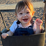 Julius joined the competition — help win amazing prizes! baby, child, swing, playground, smile, happy, sunlight, outdoor, face, clothing, denim_overall, white_shirt, hands, hair, seat, metal, shadow, nature, fun, cute