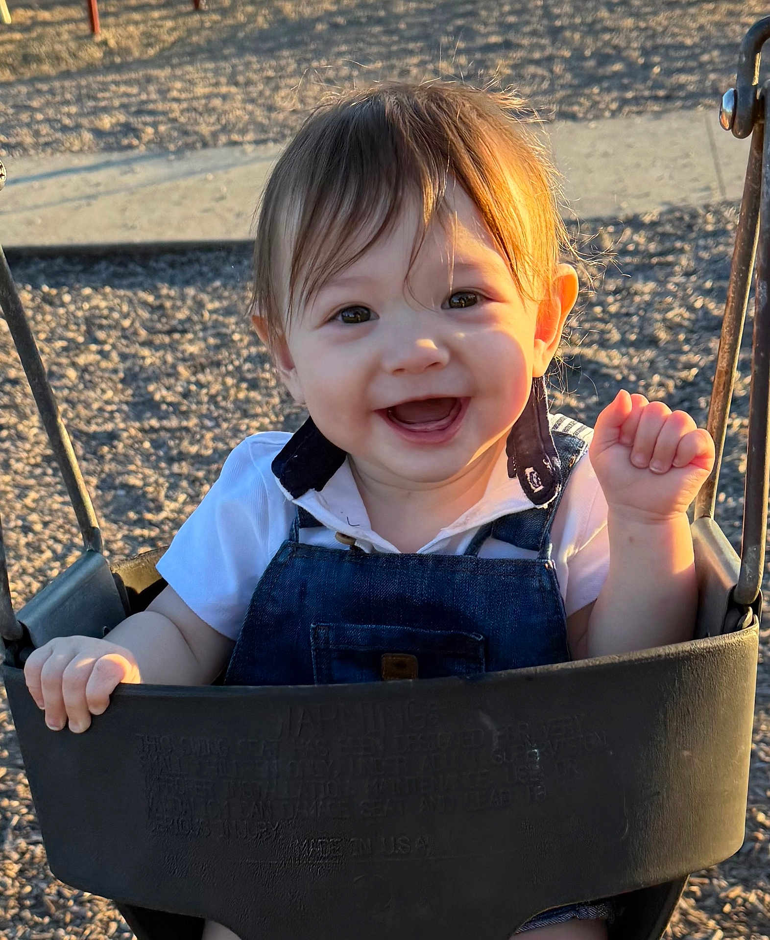 Julius joined the competition — help win amazing prizes! baby, child, swing, playground, smile, happy, sunlight, outdoor, face, clothing, denim_overall, white_shirt, hands, hair, seat, metal, shadow, nature, fun, cute