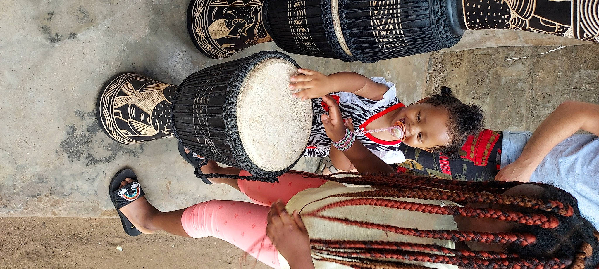 Loéline a rejoint le concours — aidez-le/la à gagner de superbes lots ! arm, audio_equipment, baby_toddler_clothing, black, clothing, drum, foot, fun, hand, hand_drum, headgear, human_leg, idiophone, joy, leg, membranophone, musical_instrument, organ, person, smile
