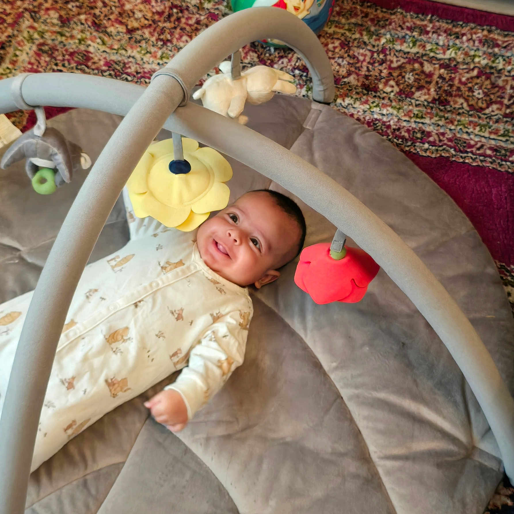 Jibran is registered to the contest to win money with this photo: baby, baby_gym, baby_toys, child, colorful, cozy, cute, face, happy, indoor, infant, lying_down, onesie, patterned_rug, play_mat, plush, portrait, smile, soft_toys, toy