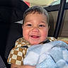 baby, child, car_seat, blanket, smile, happy, face, rosy_cheeks, clothing, checkered_shirt, indoor, person, portrait, cute, hands, young_child, infant, seat_belt, car, soft_texture