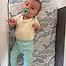 Enzo is registered to the contest to win money with this photo: baby, infant, pacifier, playpen, mattress, patterned, clothing, pastel_colors, looking, curious, hands, lying_down, indoor, soft_lighting, face, head, feet, cute, child, young