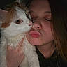 cat, woman, person, pet, portrait, close_up, orange_and_white, fur, whiskers, nose, face, eyes, closed_eyes, cuddling, holding, indoor, dim_lighting, selfie, affection, human_animal_bond