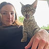woman, kitten, cat, animal, pet, yawning, hand, portrait, outdoor, porch, natural_light, relaxing, young_adult, tabby, feline, casual, resting, closeup, expression, companion