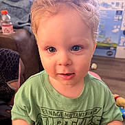 Ronnie is registered to the contest to win money with this photo: blanket, blue_eyes, casual_clothing, child, couch, curly_hair, cute, floor, green_tshirt, home, indoor, living_room, person, playful, portrait, smiling, teenage_mutant_ninja_turtles, toddler, toy, young_child
