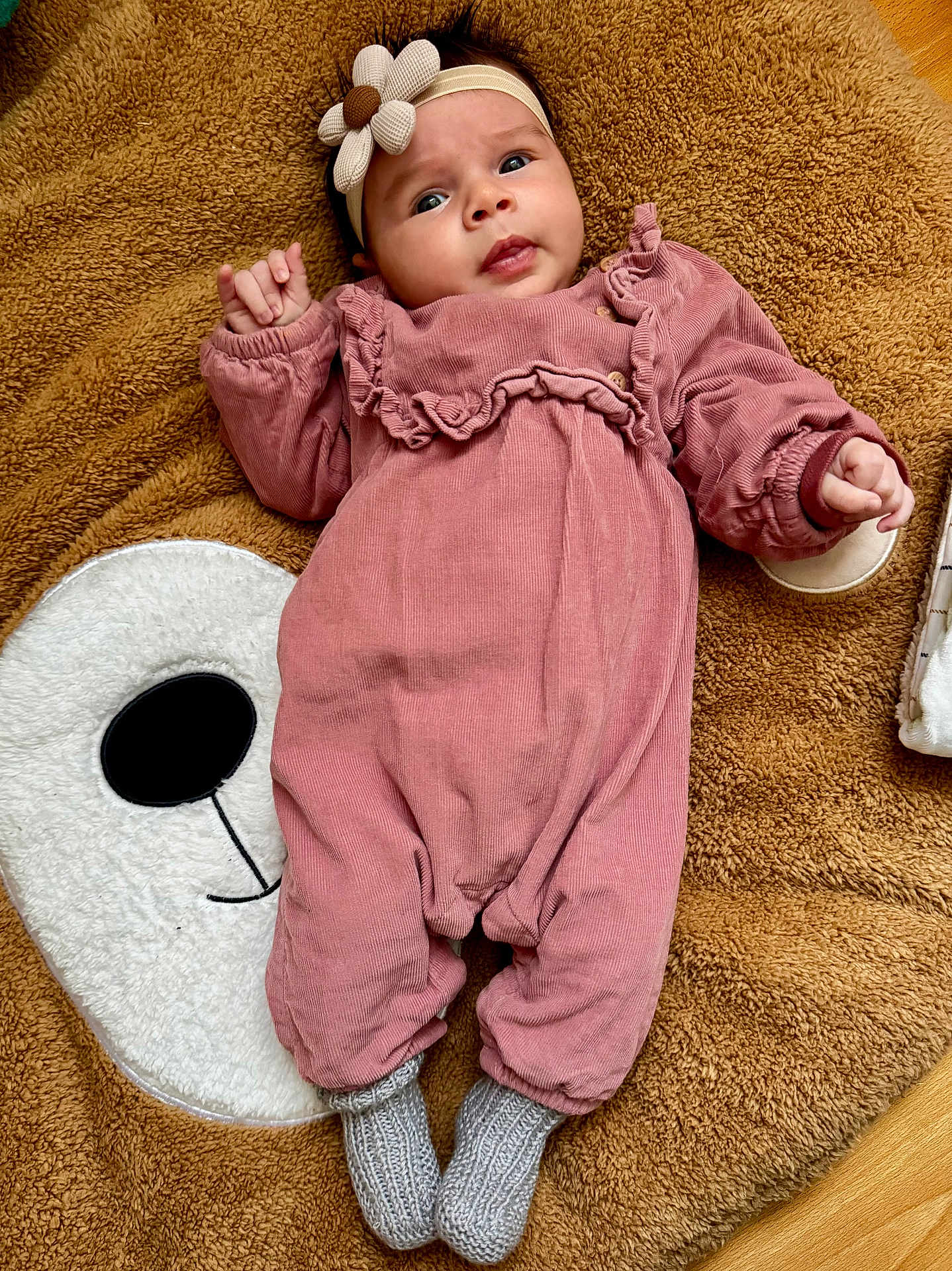 Serena a rejoint le concours — aidez-le/la à gagner de superbes lots ! baby, infant, pink_romper, gray_socks, headband, flower_headband, brown_blanket, soft_texture, white_bear_face, floor, curious_expression, lying_down, child, cute, indoors, portrait, small_hands, cozy, warm_clothing, knitted_socks