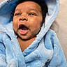baby, child, blue_robe, hood, smiling, happy, cute, infant, portrait, closeup, soft_texture, warm_clothing, indoor, person, face, expression, skin, black_hair, adorable, cozy