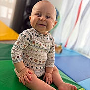 Elyo participe au concours pour gagner de l'argent avec cette photo : baby, bald, blurred_background, child, colorful, cute, face, hands, happy, indoor, infant, legs, onesie, patterned_clothing, playmat, portrait, shallow_depth_of_field, sitting, smiling, toes