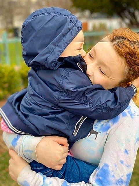 Zander is registered to the contest to win money with this photo: baby, baby_products, child, grass, happy, hug, interaction, love, outerwear, person, photography, sitting, smile, toddler, tree