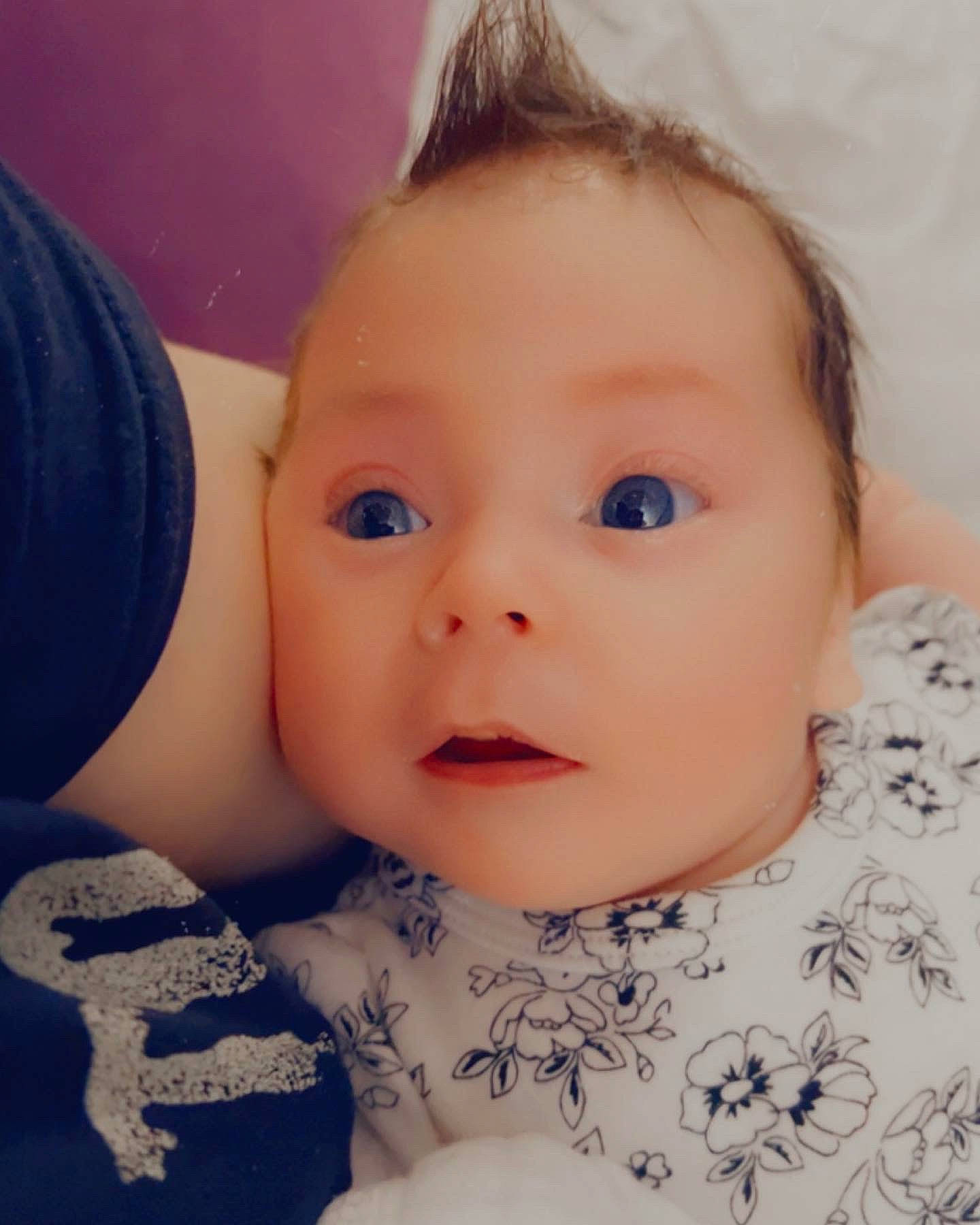 Lilith is registered to the contest to win money with this photo: baby, baby_toddler_clothing, brown_hair, cheek, child, ear, eyelash, fashion_accessory, hair_accessory, happy, headgear, iris, lip, nose, pattern, person, skin, sleeve, smile, surprise