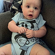 Darryl is registered to the contest to win money with this photo: baby, child, infant, sitting, armchair, couch, blanket, cartoon_clothing, blue_outfit, portrait, indoors, home, wide_eyed, open_mouth, smiling, hands, legs, bare_feet, vintage_trunk, cozy