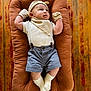 Elias joined the competition — help win amazing prizes! baby, infant, cushion, plush, clothing, shorts, mittens, hat, socks, person, child, face, smile, indoor, wooden_floor, relaxing, cute, young, fashion, portrait