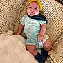 baby, smiling, headband, romper, knitted_blanket, cozy, indoor, infant, cute, child, soft_texture, happy, resting, person, portrait, comfortable, blue_socks, plush, candid, warm
