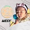 Julia joined the competition — help win amazing prizes! newborn, baby, infant, sleeping, portrait, face, pink_bow, headband, pacifier, blanket, milestone, two_weeks, wooden_sign, text, yellow_clothing, bib, indoor, close_up, nursery, adorable