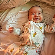 Sire joined the competition — help win amazing prizes! baby, smiling, dinosaur_print, onesie, bed, blanket, sheet, infant, happy, child, face, person, sleepwear, crawling, cute, lying_down, indoors, cozy, soft, warm