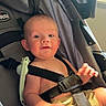 baby, child, stroller, seatbelt, indoors, curious, smile, face, person, clothing, window, light, daylight, sitting, childcare, infant, safety, happy, cute, young