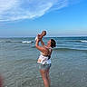baby, woman, beach, ocean, water, sky, waves, summer, vacation, child, outdoor, happy, playful, fun, mother, holding, standing, casual_clothing, nature, shore