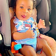 Honesty joined the competition — help win amazing prizes! baby, child, car_seat, bow, dress, blue, pink, cushion, infant, cute, tongue_out, clothing, footwear, ribbon, seatbelt, indoor, person, happy, portrait, car_interior