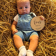 Kamari joined the competition — help win amazing prizes! baby, infant, child, overalls, socks, hay, nest, sign, four_months, portrait, cute, sitting, holding, expression, warm_lighting, outdoor, nature, closeup, soft_skin, small_hand