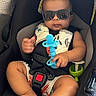Kamari is registered to the contest to win money with this photo: baby, child, car_seat, sunglasses, toy, teether, infant, seatbelt, reflection, person, indoor, clothing, shorts, foot, hand, cute, safety, seat, expression, accessory