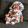 baby, crying, child, couch, gray_couch, hat, clothing, socks, infant, toddler, indoor, upset, cute, patterned_clothing, facial_expression, sitting, textile, comfort, emotion, portrait