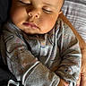 baby, sleeping, infant, hands, clothing, dinosaur_pattern, rainbow_pattern, closeup, portrait, peaceful, cozy, soft_light, human, child, cute, resting, person, fabric, texture, indoor