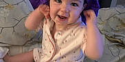 Skye joined the competition — help win amazing prizes! baby, child, smiling, bed, bedding, blanket, purple_bonnet, headwear, infant, cute, happy, indoors, person, pajamas, playful, sitting, soft_lighting, floral_pattern, cozy, portrait