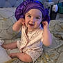 baby, child, smiling, bed, bedding, blanket, purple_bonnet, headwear, infant, cute, happy, indoors, person, pajamas, playful, sitting, soft_lighting, floral_pattern, cozy, portrait