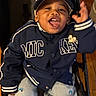 Donico-Juan joined the competition — help win amazing prizes! child, toddler, smiling, jacket, cap, mickey_mouse, clothing, person, indoor, wooden_floor, pants, sitting, happy, face, portrait, baby, expression, young_child, seat, casual
