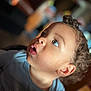 child, curly_hair, face, portrait, blue_shirt, indoor, soft_light, close_up, expression, young_child, person, cute, curious, skin, eyeball, ear, mouth, nose, head, human