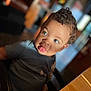 Jac is registered to the contest to win money with this photo: toddler, child, curly_hair, blue_eyes, tongue_out, playful, portrait, indoor, warm_light, blurred_background, cute, smiling, casual_clothing, seated, face, person, expression, young_child, baby, photography