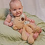 baby, teddy_bear, smile, cute, infant, plush_toy, blanket, soft_lighting, indoors, child, happy, person, cuddly, sitting, face, small_feet, clothing, cozy, portrait, playful