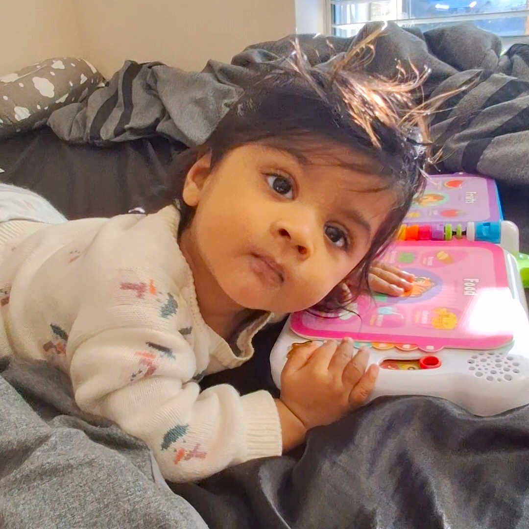 Easan is registered to the contest to win money with this photo: baby, bed, blanket, child, clothing, curious, educational_toy, expression, face, hand, head, indoor, lying_down, person, playing, room, sleeve, sunlight, toy, window