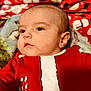 baby, infant, face, child, red_clothing, holiday_outfit, candy_cane, bells, christmas_theme, wrapped_presents, background, closeup, portrait, cute, young_child, festive, holiday, indoors, soft_lighting, smiling