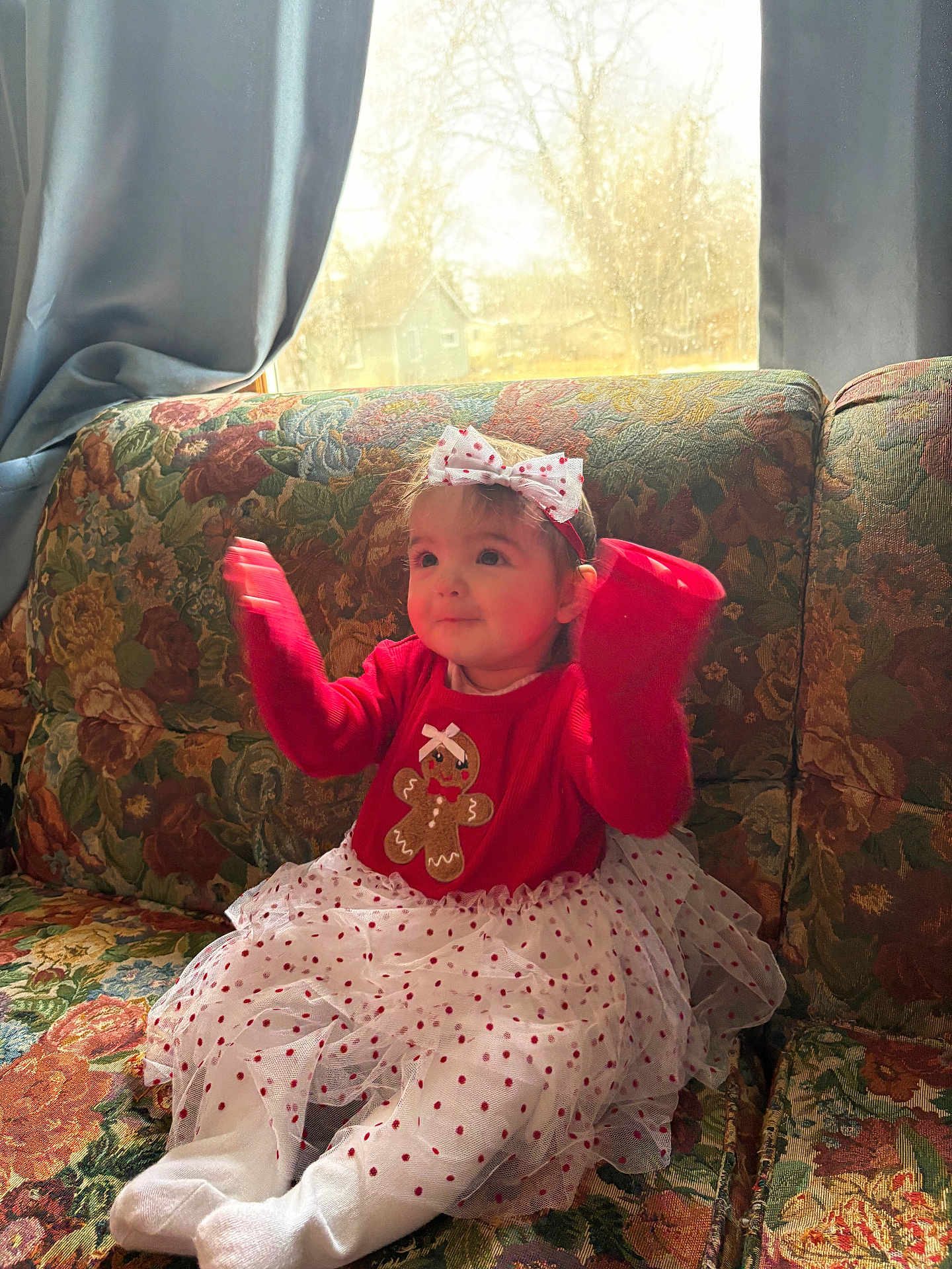 Jamboree Davis is registered to the contest to win money with this photo: toddler, child, red_sweater, gingerbread_man, white_tutu, polka_dots, headband, bow, couch, floral_pattern, window, daylight, indoor, happy, smiling, sitting, hands_up, cute, festive, cozy