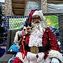 santa_claus, cat, chair, holiday, christmas, outdoor, tree, lights, leash, glasses, costume, beard, pillow, fabric, building, brick_wall, plaid_blanket, glove, festive, person