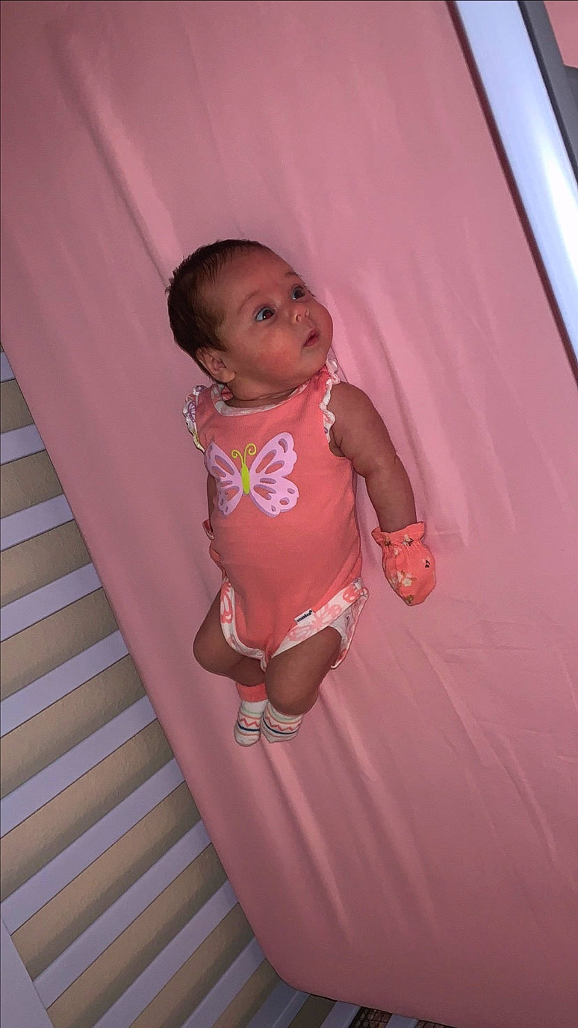 Liana is registered to the contest to win money with this photo: arm, baby, baby_toddler_clothing, cheek, elbow, finger, flooring, fun, happy, human_body, human_leg, knee, leg, magenta, person, pink, room, t_shirt, thigh, toddler