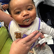 Cherish joined the competition — help win amazing prizes! baby, bib, food_stain, hand, tissue, clothing, face, person, child, messy, curious, indoor, holding, cute, expression, casual, closeup, skin, sitting, adult