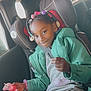 braids, car_interior, car_seat, casual_clothing, child, colorful_beads, girl, green_jacket, happy, holding_object, indoor, person, playful, portrait, seatbelt, sitting, smile, toy, window, young_child