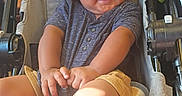 Zyair is registered to the contest to win money with this photo: baby, baby_bottle, child, clothing, cute, expression, face, foot, hair, hand, happy, indoors, person, seatbelt, shirt, shorts, sitting, smiling, stroller, toddler