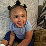 toddler, child, smiling, tongue_out, blue_shirt, navy_pants, pigtails, couch, pillows, indoor, happy, cute, baby, person, seated, homedecor, skin, face, hand, footwear