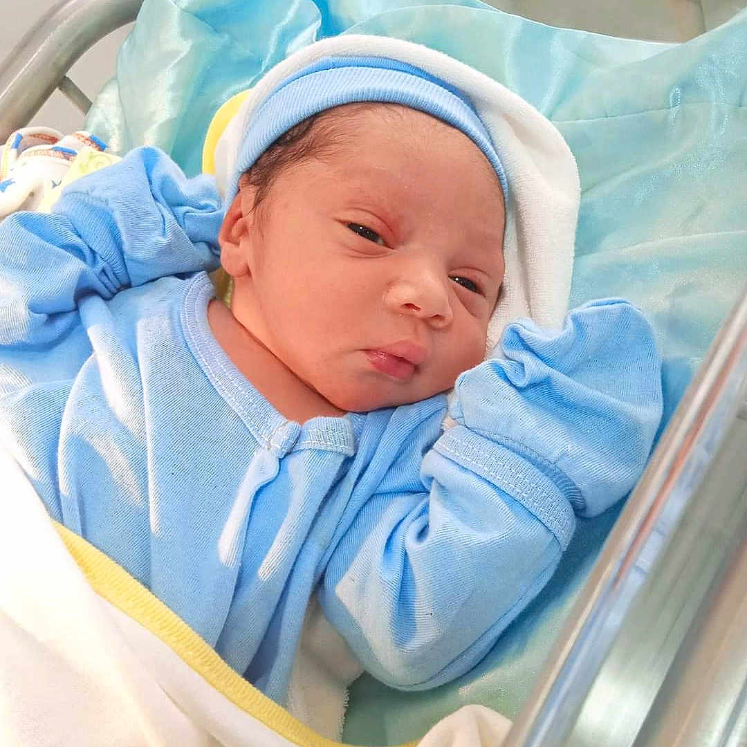 Jacquelyn is registered to the contest to win money with this photo: newborn, baby, infant, blue_clothing, hospital, bassinet, blanket, sleepwear, hat, person, cute, resting, indoors, child, baby_boy, portrait, medical_equipment, soft_texture, cozy, sleepy