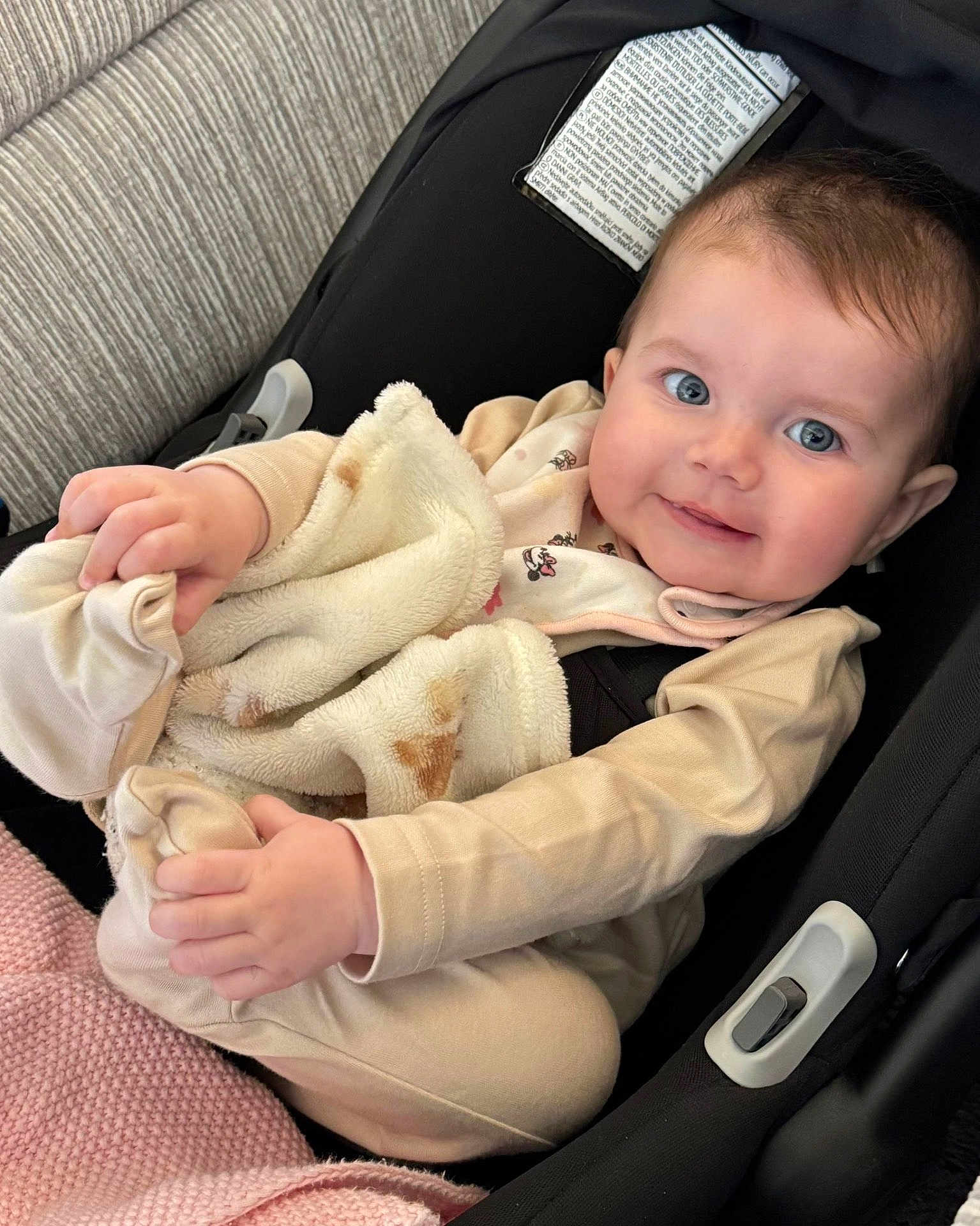 Wren is registered to the contest to win money with this photo: baby, infant, blanket, car_seat, blue_eyes, smiling, clothing, soft_texture, cute, child, indoors, seat_belt, comfort, toddler, portrait, hands, face, closeup, pink_blanket, warm