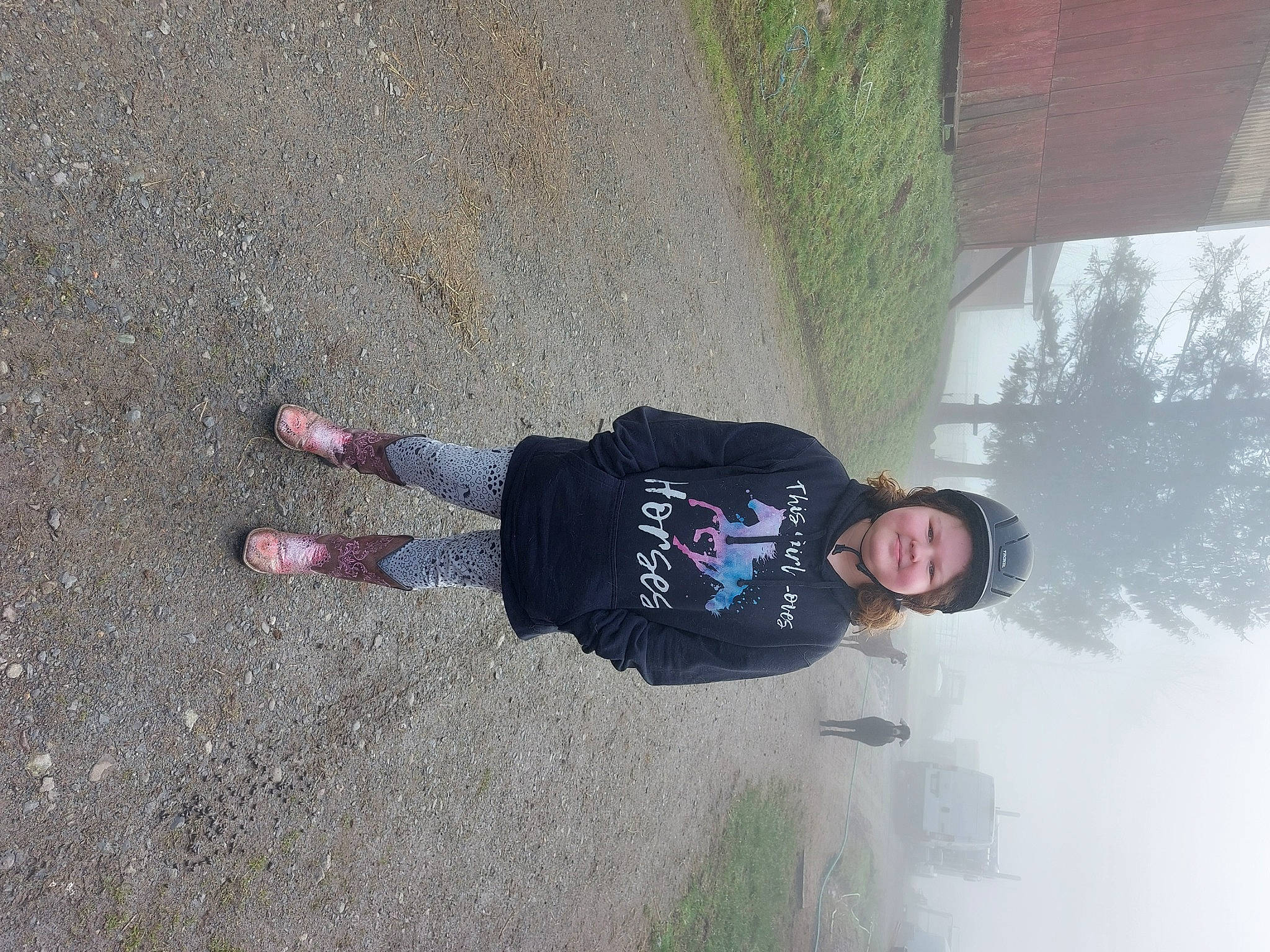 Baylee is registered to the contest to win money with this photo: asphalt, concrete, extreme_sport, fun, grass, headwear, joy, leisure, person, personal_protective_equipment, plant, recreation, road_surface, shadow, sidewalk, smile, soil, tar, tire, toddler