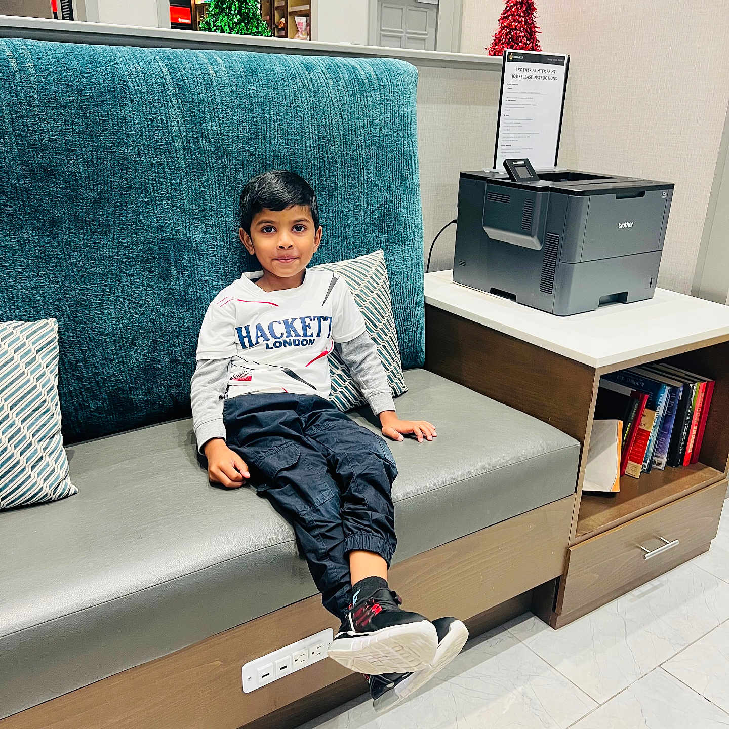 Thejus joined the competition — help win amazing prizes! bench, black_pants, books, boy, casual_clothing, child, curious_expression, cushion, floor_tiles, holiday_decorations, indoor, modern_furniture, portrait, printer, room, side_table, sitting, sneakers, tinsel, white_shirt