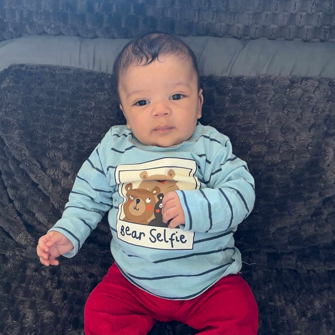 Adam a rejoint le concours — aidez-le/la à gagner de superbes lots ! baby, bear_selfie, blanket, casual, child, clothing, comfortable, cute, expression, fabric, face, indoors, infant, pants, portrait, shirt, shoes, sitting, striped, textile