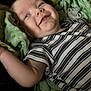 baby, child, smile, striped_shirt, blanket, green_blanket, pacifier, infant, lying_down, happy, cheeky, soft_texture, closeup, face, arm, clothing, person, comfortable, indoors, cute